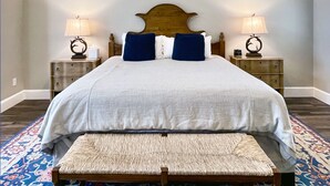 A neatly made bed with a wooden headboard, two bedside tables with lamps, and a bench with a patterned cushion. - Romantic Couples Suite in the Poconos (Stroudsburg)