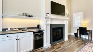 Een moderne keuken met witte kasten, een ingebouwde oven, een granieten aanrechtblad en een open haard.