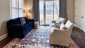 Een zithoek met een blauwe bank, een kamerkleed met patroon en een geruite stoel.