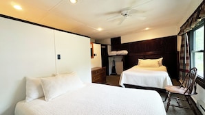 Une chambre d’hôtel avec deux lits, un ventilateur de plafond et une fenêtre avec des rideaux.