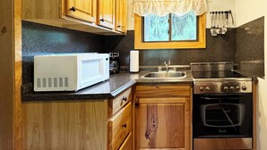 Une cuisine compacte dotée de meubles en bois, d’un four à micro-ondes, d’une machine à café, d’un évier et d’une cuisinière.