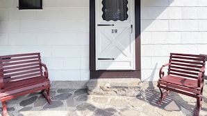 A white door with a number 19, two wooden benches, and a stone-paved entrance. - Poconos Rustic 1BR in the Poconos on Private Resort (Stroudsburg)