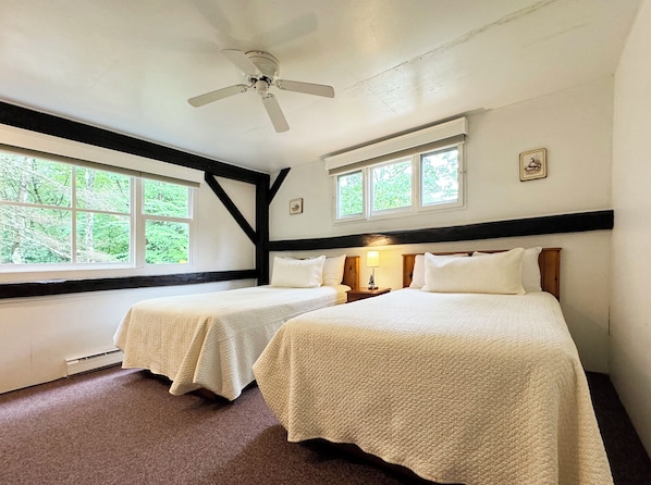 A room with two beds, a ceiling fan, and large windows with a view of trees. - Poconos Rustic 1BR in the Poconos on Private Resort (Stroudsburg)