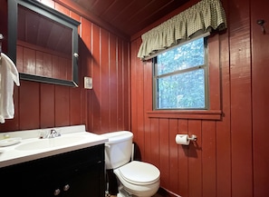 A bathroom with a white sink, a toilet, and a window with a checkered valance. - Charming Lake Front Log Cabin with Fire Pit in the Poconos (Stroudsburg)