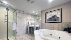 A modern bathroom with a glass shower enclosure, a freestanding bathtub, a sink, and a large mirror.