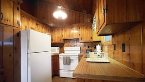 Cocina con paneles de madera, refrigerador, estufa, microondas y encimera de madera.