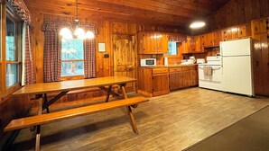 Una cocina tipo cabaña de madera con una mesa y bancos de madera, un refrigerador y armarios de madera.