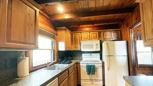 Una cucina funzionale con pensili e basi in legno, un forno a microonde, un fornello e un frigorifero.