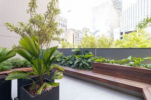 A rooftop garden with a wooden bench and potted plants. - Vossa Bossa Think Republica (São Paulo)