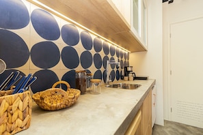 Una cocina con salpicadero de azulejos, pileta de acero inoxidable y muebles de madera.