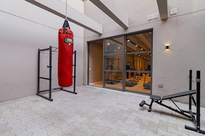 A gym with a punching bag, weight bench, and exercise equipment.