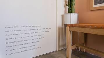 Eine Wand mit einem portugiesischen Gedicht, ein Kaktus in einem weißen Topf und eine hölzerne Bank.