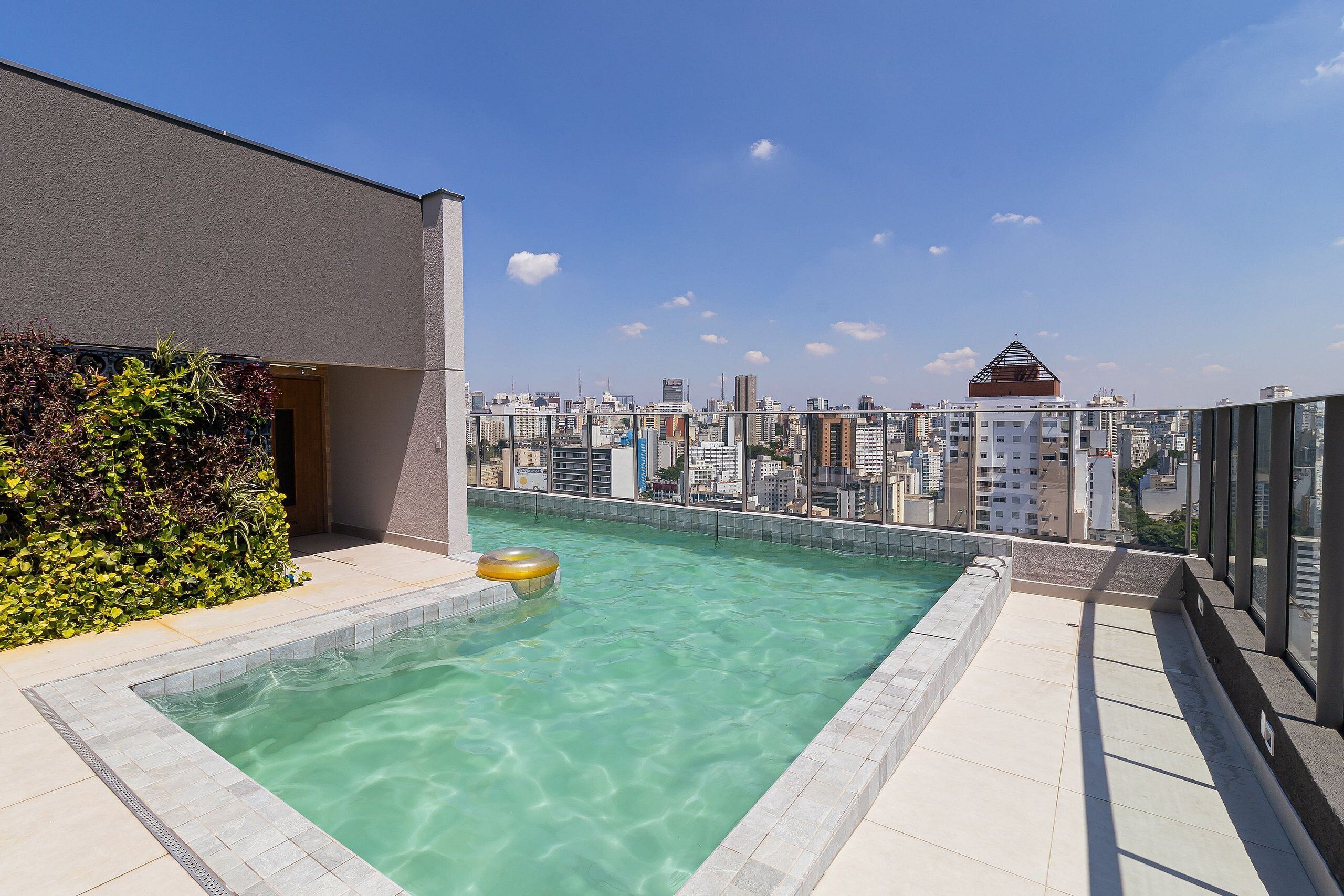A rooftop swimming pool with clear water, surrounded by a cityscape view.