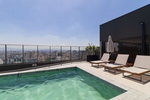 A rooftop pool with clear water, surrounded by lounge chairs and a city view. - Vossa Bossa Think Republica (São Paulo)