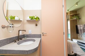 A bathroom with a large mirror, a sink with a modern faucet, and two shelves with plants. - Vossa Bossa Think Republica (São Paulo)