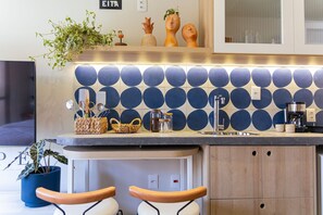 A modern kitchen with a blue circular tile backsplash, wooden cabinets, and a countertop with various kitchen items.