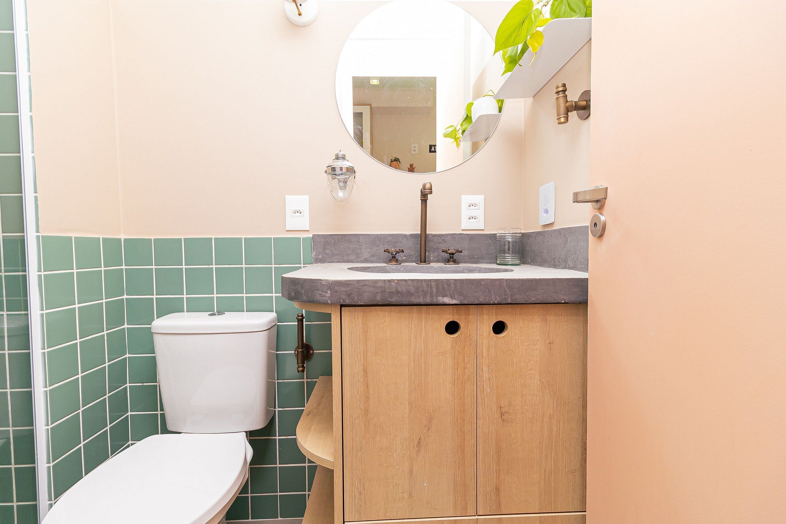 A bathroom with a toilet, sink, and wooden cabinet.