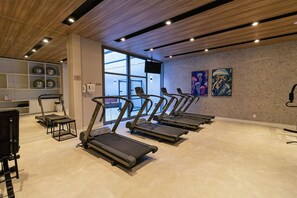 Ein Fitnessraum mit Laufbändern, einem Ergometer und einer Gewichtbank.