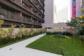 A modern building with multiple balconies and a well-maintained garden area with grass and plants.