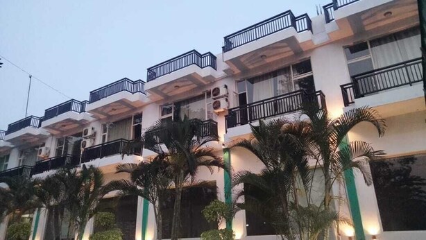 A multi-story hotel with balconies, air conditioning units, and a well-lit facade.