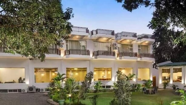 A multi-story hotel with balconies, large windows, and a well-maintained garden. - Novel Resort by Urban (Ramnagar)