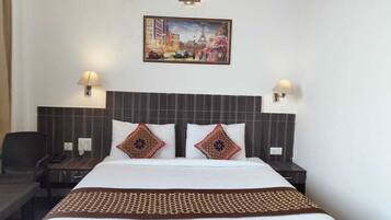 A hotel room with a large bed, two bedside lamps, a nightstand, a chair, and a painting on the wall.