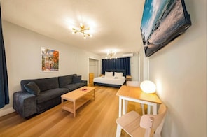 A modern hotel room with a sofa, a bed, a desk, and a chair.