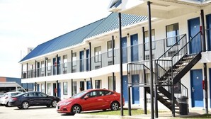 Ein mehrstöckiges Motel mit blauem Dach und weißen Außenwänden, ausgestattet mit einer zentralen Treppe und mehreren Balkonen.