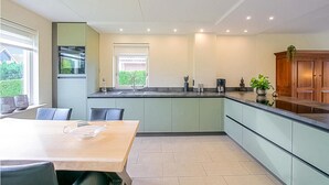 Una cocina moderna con comedor, que cuenta con una isla grande, armarios empotrados y vistas a través de la ventana.
