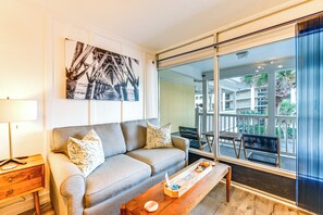 A modern living room with a sofa, a coffee table, and a large window offering a view of the outdoors.