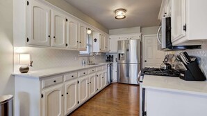 Una cocina con gabinetes blancos, un refrigerador de acero inoxidable, una estufa y un microondas.