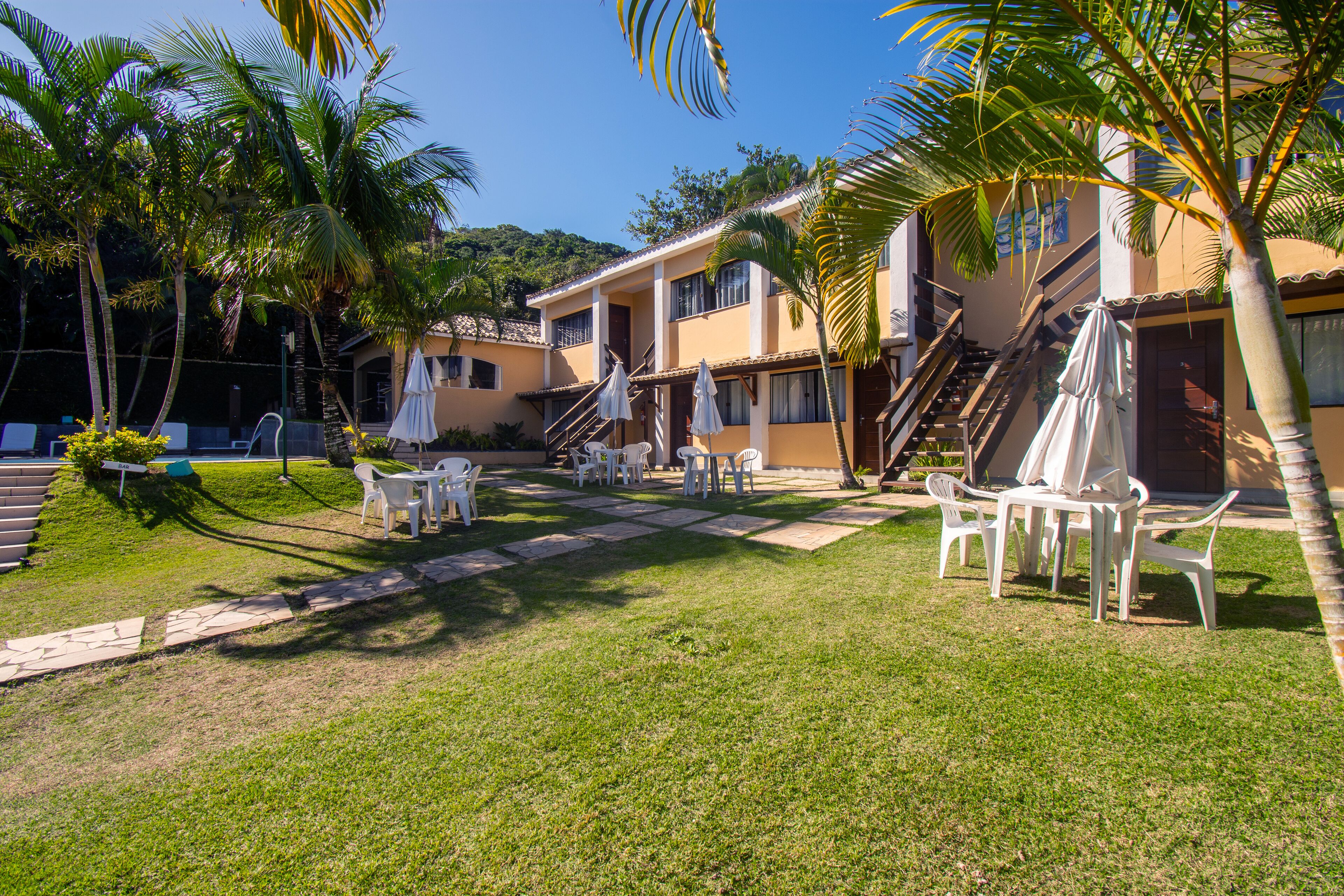 A courtyard with outdoor seating, palm trees, and a building with a staircase.