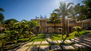 Un patio con un camino de piedra, palmeras y mobiliario exterior.