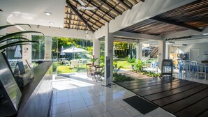 Un espacio interior amplio con un muro de cristal que da a un jardín, una terraza de madera y un techo con un diseño único.
