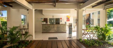 A reception area with a wooden floor, a reception desk, and potted plants.