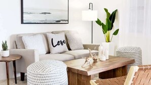 Un salon moderne avec un canapé, une table basse et une table d’appoint.
