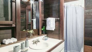 A bathroom with a wooden interior, a white sink, and a large mirror.