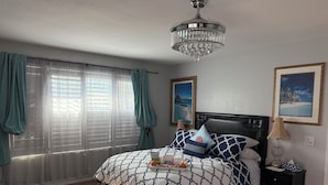 A bedroom with a bed, a nightstand, a chandelier, and two framed pictures on the wall. - Romantic Coastal Private Room is located 10 minutes from all sightseeing places  (Oxnard)