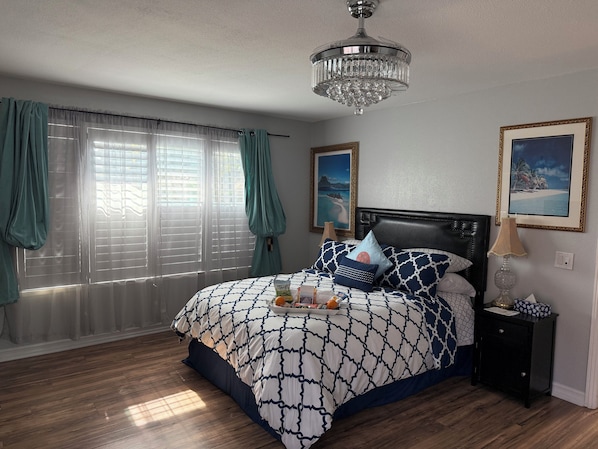 A bedroom with a bed, a nightstand, a chandelier, and two framed pictures on the wall. - Romantic Coastal Private Room is located 10 minutes from all sightseeing places (Oxnard)