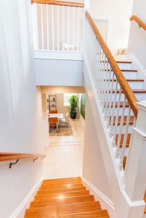 A staircase with wooden steps and white railings leading to a lower level. - 505 Sunset Key Estate | Luxury Courtyard Pool Home (Naples)
