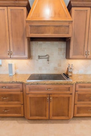 A kitchen with wooden cabinets, a stainless steel sink, and a tiled backsplash. - 505 Sunset Key Estate | Luxury Courtyard Pool Home (Naples)