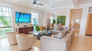 Amplia sala de estar con una televisión de pantalla plana grande, asientos cómodos y vista al exterior.