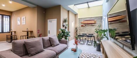 A modern living room with a sofa, coffee table, and a dining area with chairs and a table.