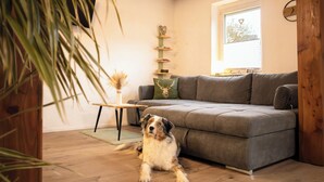 A cozy living room with a grey sofa, a wooden coffee table, and a decorative plant. - Neue, Gemütliche Ferienwohnung mit Großer Terrasse (Wildflecken)