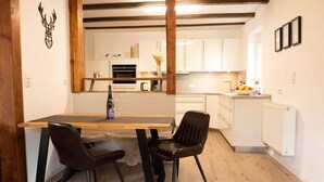 A modern kitchen with white cabinets, a wooden dining table, and two chairs. - Neue, Gemütliche Ferienwohnung mit Großer Terrasse (Wildflecken)