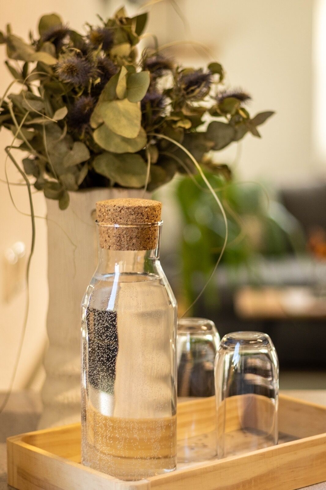 A glass bottle with a cork stopper on a wooden tray.