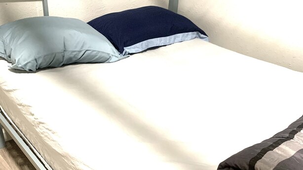 Un letto a castello con materasso bianco, cuscino blu e coperta a righe.