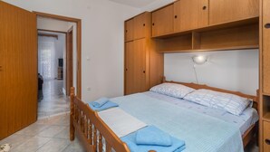 Un dormitorio con cama, armario de madera y mesita de noche.