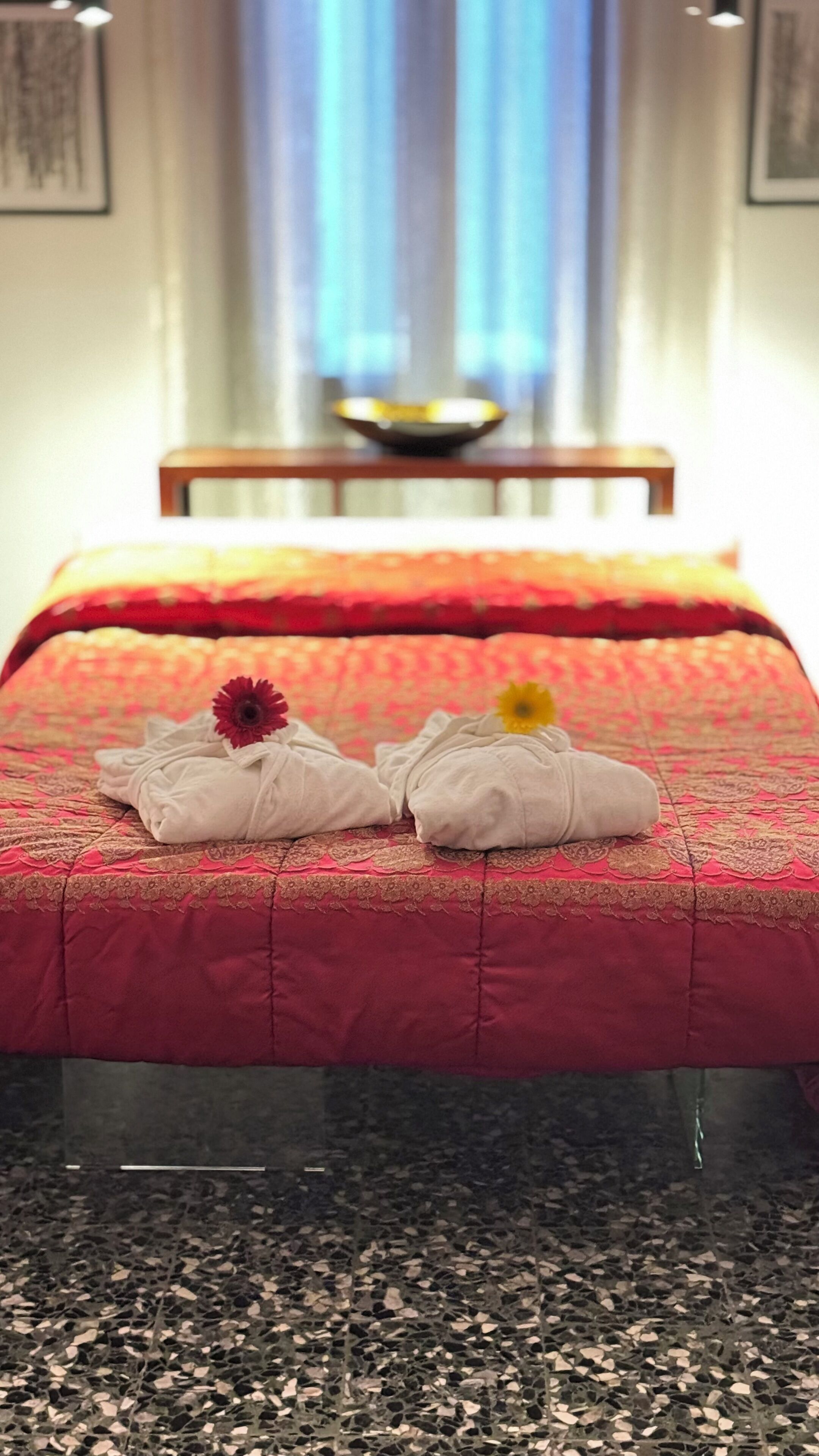 Una camera d'albergo con un letto, cuscini e una ciotola sopra la testiera.