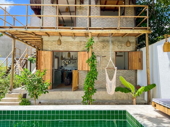 A two-story house with a kitchen, a dining area, and a small pool area.